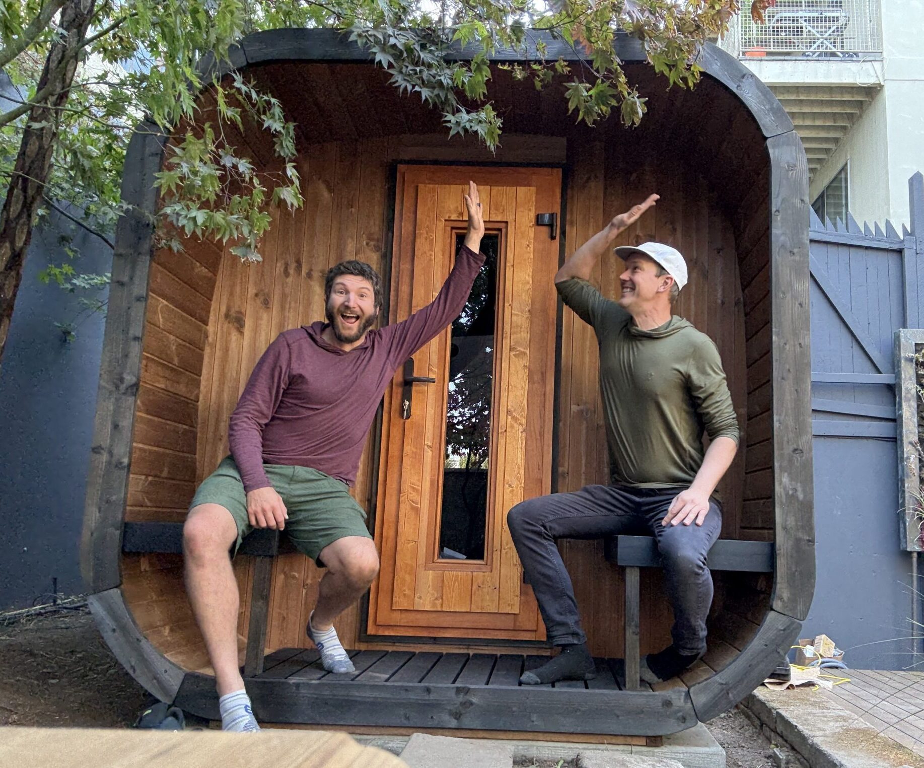 Sauna Marketplace co-founders Ben Burger and Ben Frizzell high-fiving outside a sauna